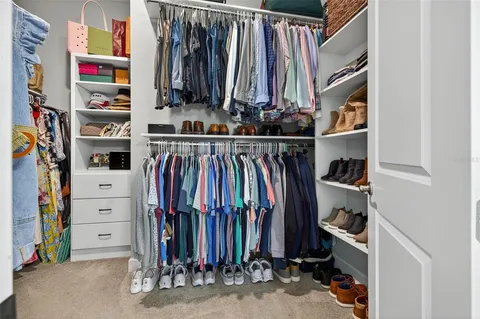 a view of walk in closet with clothes and shoes