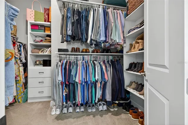a view of walk in closet with clothes and shoes
