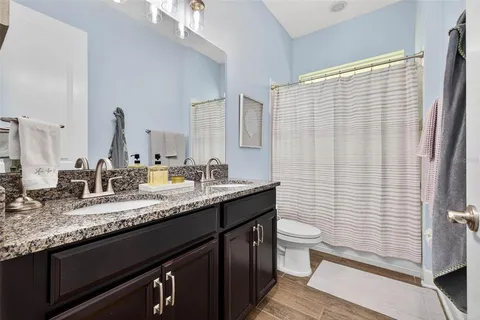 a bathroom with a granite countertop sink a toilet and a mirror