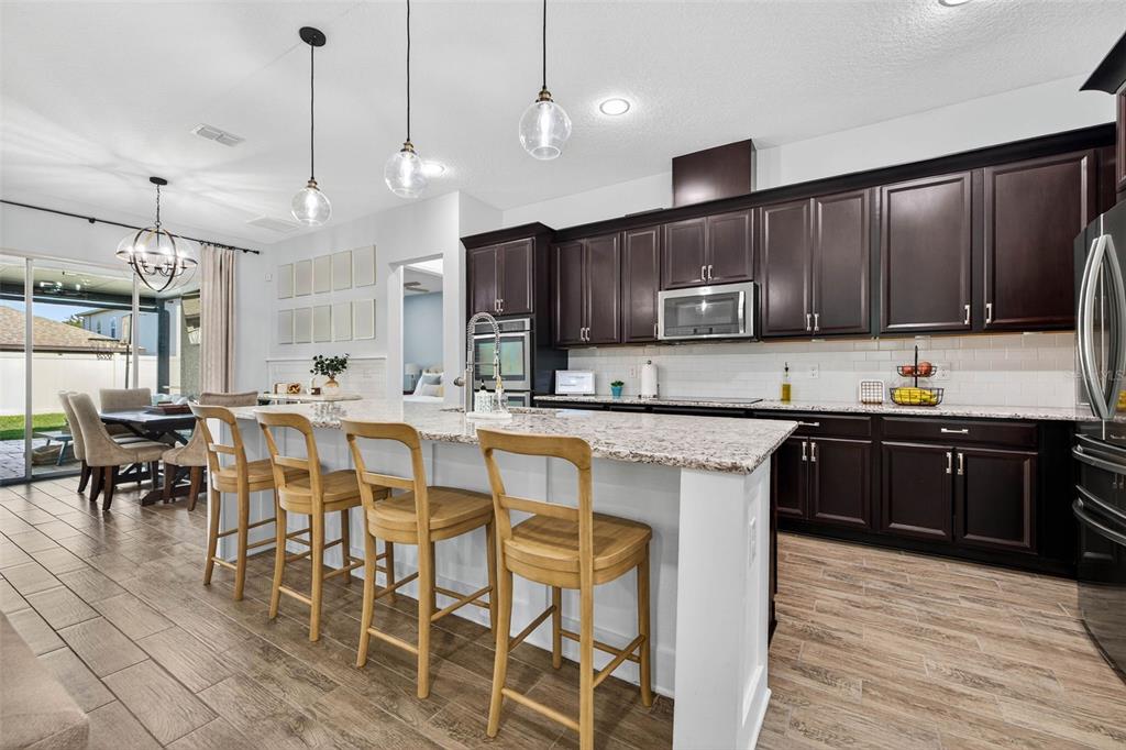 10522 Cardera Drive Riverview, FL 33578 - Photo 5 of 43 a kitchen with stainless steel appliances granite countertop wooden cabinets a stove a sink and a dining table