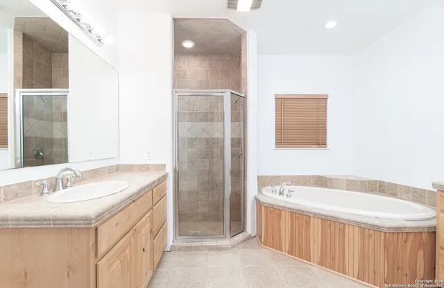 a spacious bathroom with a tub sink and mirror