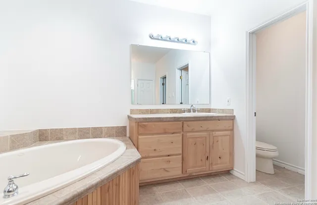 a bathroom with a granite countertop sink a toilet and a bathtub