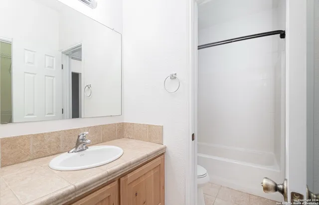 a bathroom with a granite countertop shower sink and a mirror