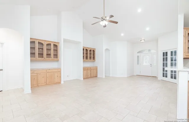 an empty room with chandelier fan and windows