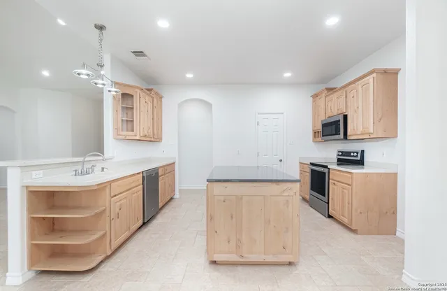 a large kitchen with stainless steel appliances granite countertop a sink and dishwasher a stove with wooden floor
