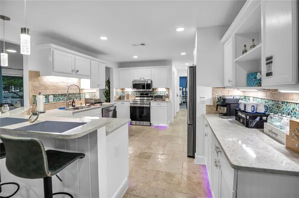 a kitchen with stainless steel appliances granite countertop a stove top oven a sink dishwasher and a refrigerator with the cabinets