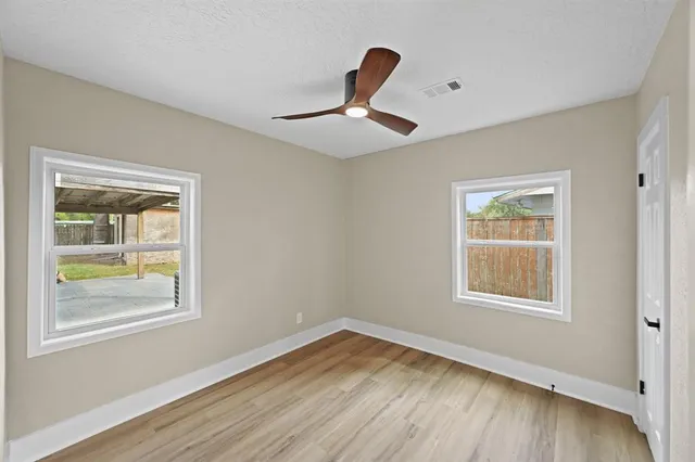 a view of empty room with wooden floor and fan