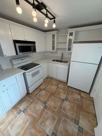 a kitchen with a stove a microwave and white cabinets