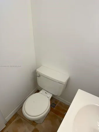a white toilet sitting next to a white wall
