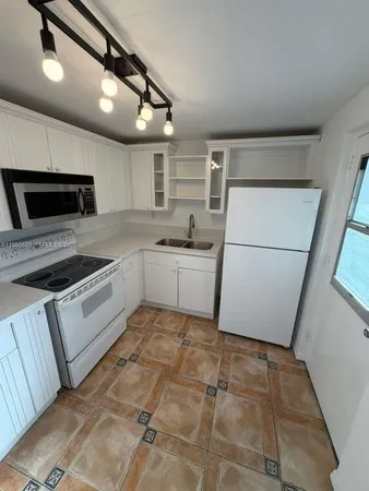 a kitchen with a sink a refrigerator and cabinets