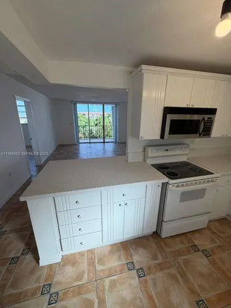 a kitchen with granite countertop white cabinets and white appliances