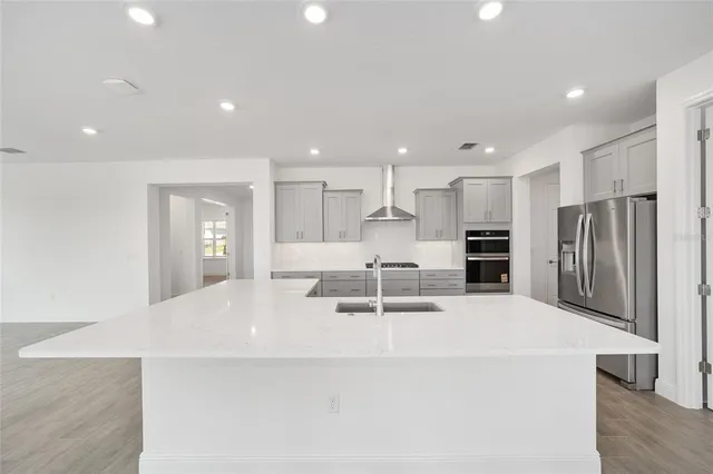 a large white kitchen with a refrigerator a oven and a sink