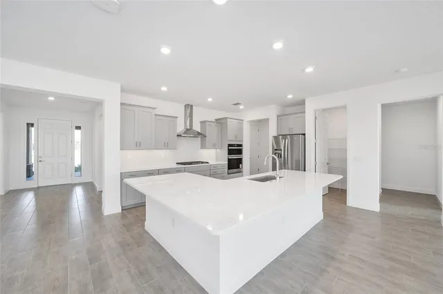 a large white kitchen with wooden floor and a sink