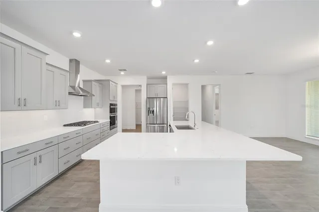 a large white kitchen with kitchen island a sink a stove and refrigerator