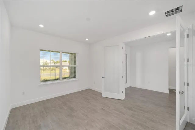 an empty room with wooden floor and windows