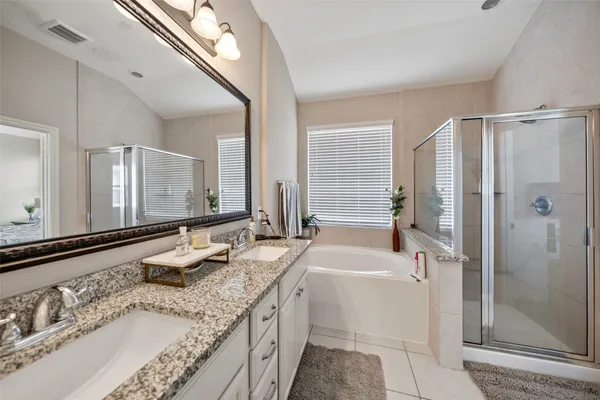 a bathroom with a granite countertop double vanity sink and mirror with shower