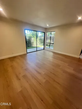 an empty room with wooden floor and glass door