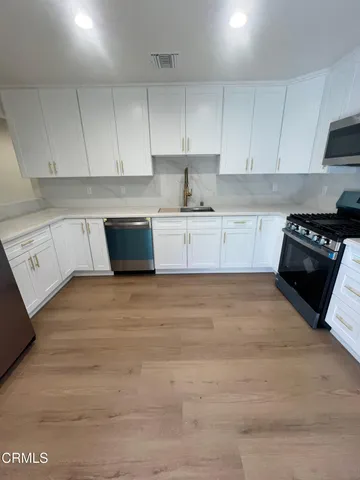 a kitchen with granite countertop white cabinets and black appliances