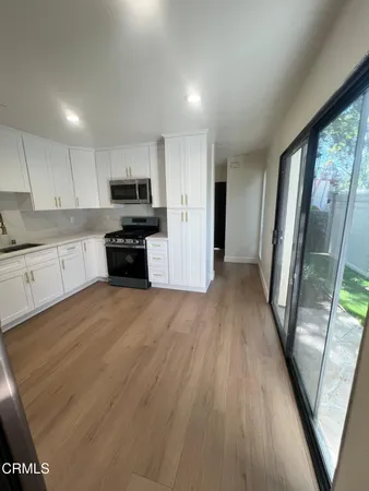 a kitchen with granite countertop a refrigerator a sink a stove a microwave and wooden floor