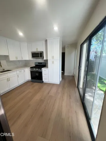 a kitchen with granite countertop a refrigerator a sink a stove a microwave and wooden floor