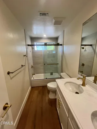 a bathroom with a sink a toilet a mirror and shower