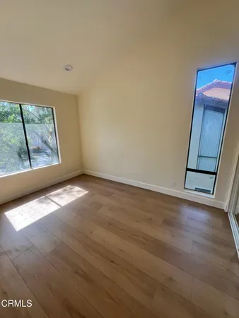 an empty room with wooden floor and windows