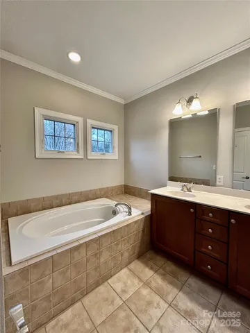 a spacious bathroom with a tub sink and mirror