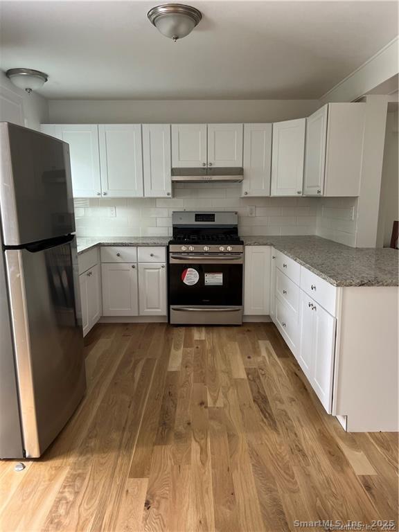 144 Rakoczy Avenue Fairfield, CT 06824 - Photo 3 of 19 a kitchen with granite countertop white cabinets and stainless steel appliances