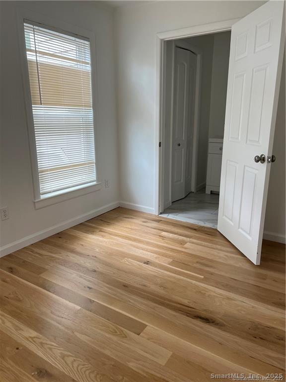 144 Rakoczy Avenue Fairfield, CT 06824 - Photo 8 of 19 an empty room with wooden floor and a window