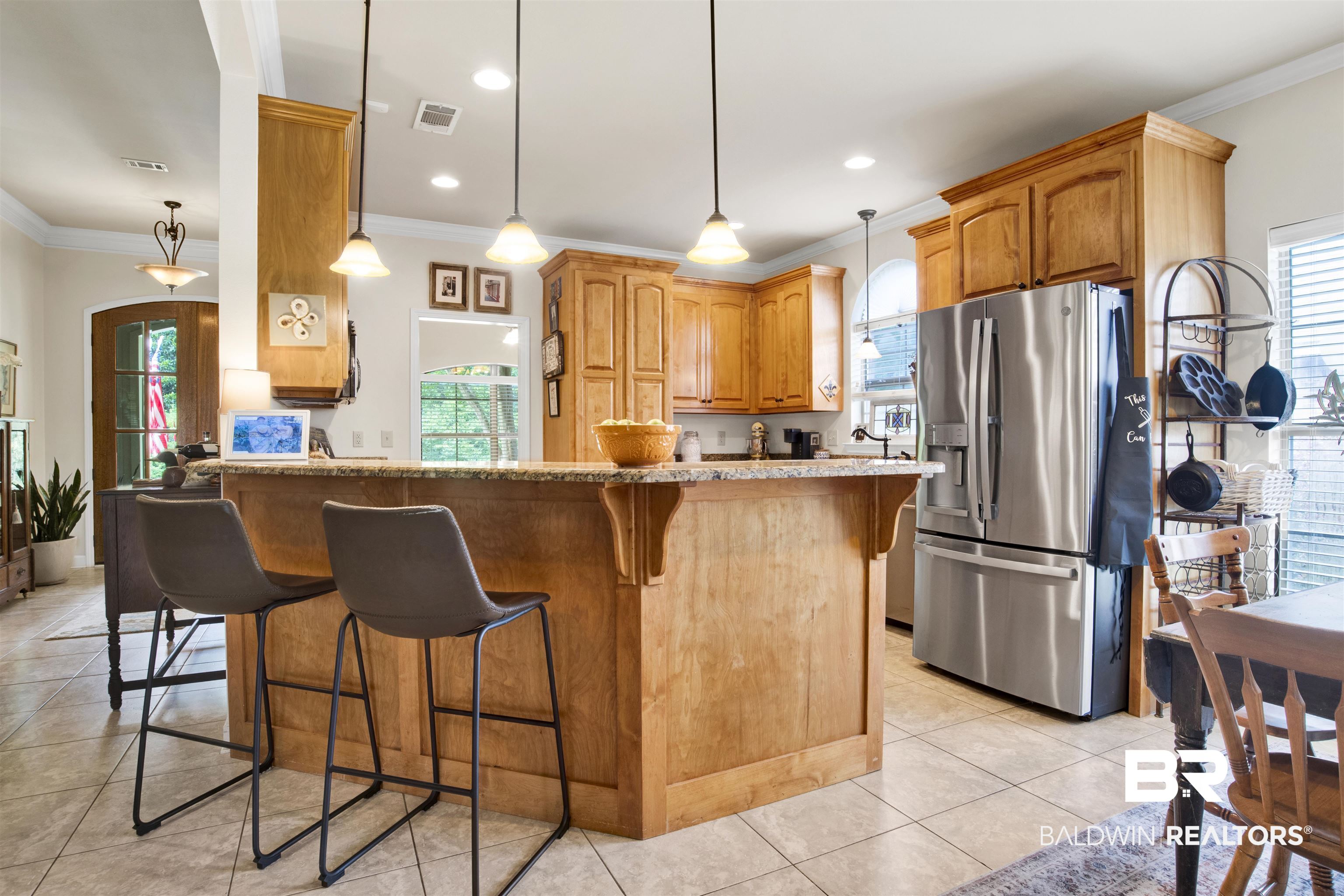 10368 Gayfer Rd Extension Fairhope, AL 36532 - Photo 6 of 43 Open-concept kitchen featuring a spacious island with seating, warm wood cabinetry, granite countertops, stainless steel appliances, and tile flooring