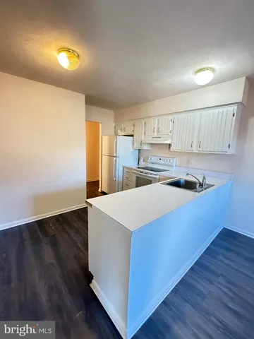 a kitchen with wooden floors and white cabinets