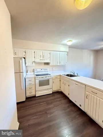 a kitchen with a white cabinets and wooden floor