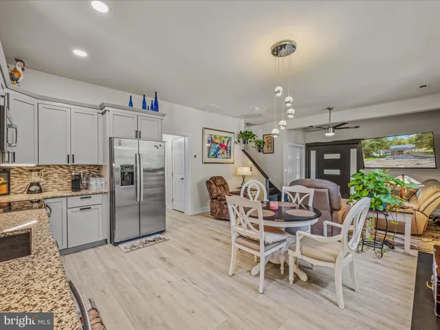 a kitchen with stainless steel appliances granite countertop a dining table chairs refrigerator and sink