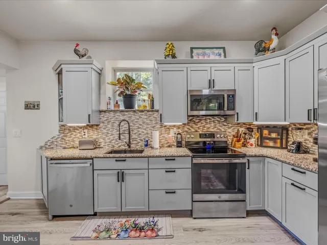 a kitchen with granite countertop a sink stove and microwave