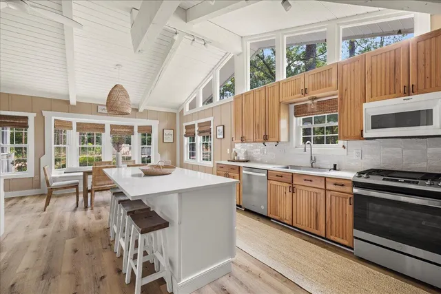 a kitchen with stainless steel appliances granite countertop a stove a sink dishwasher and a refrigerator with wooden floor