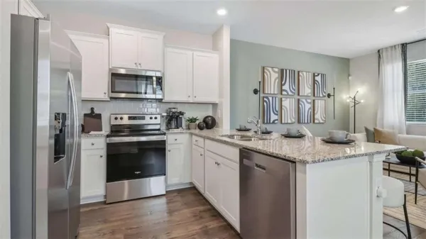 a kitchen with stainless steel appliances granite countertop a refrigerator a stove and a sink