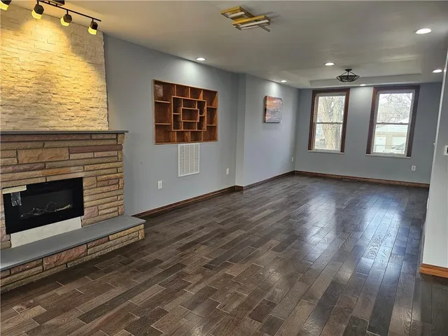 a view of an empty room with wooden floor fireplace and a window