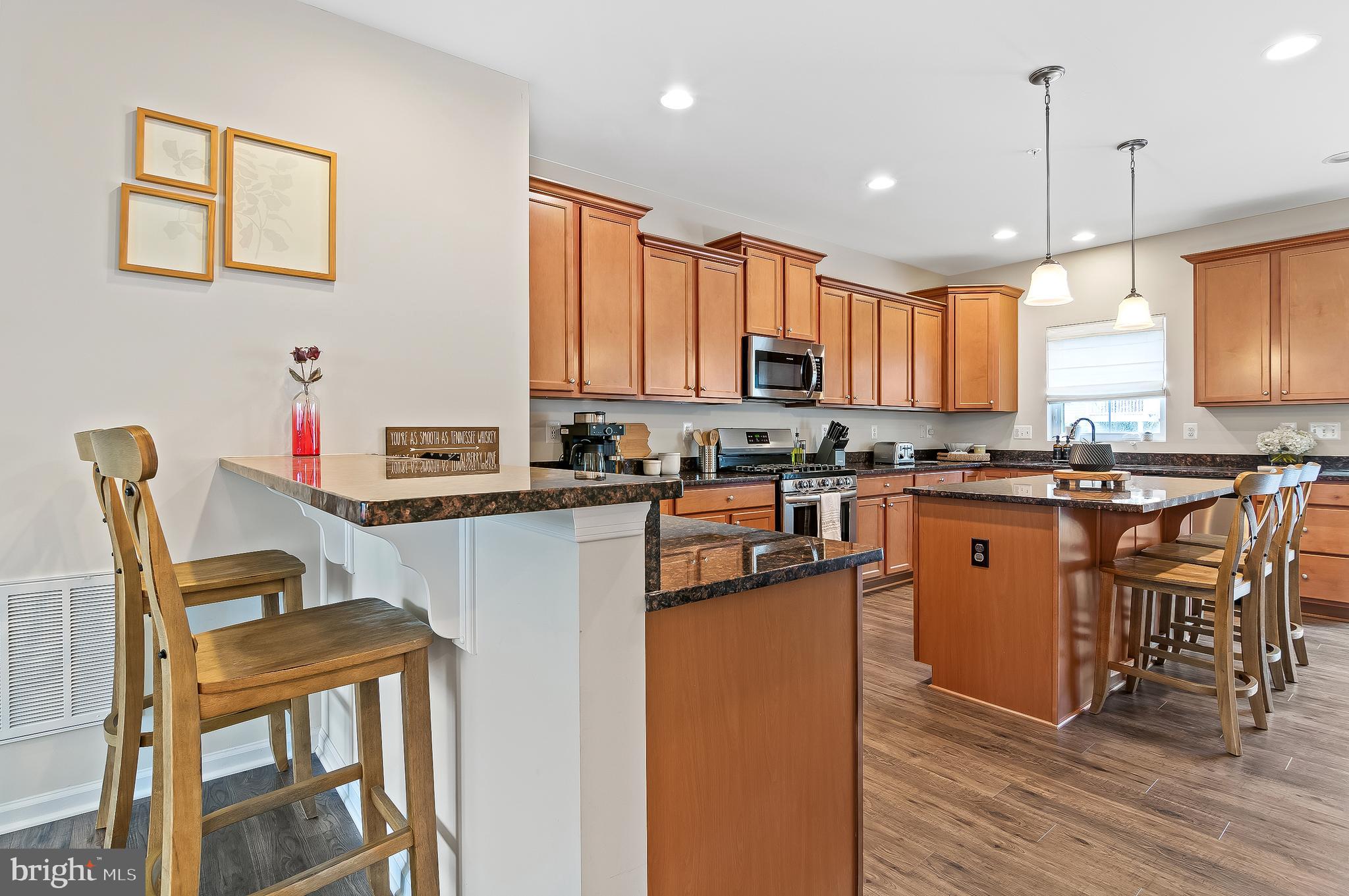 1022 Linden Drive Hanover, MD 21076 - Photo 14 of 42 a kitchen with stainless steel appliances granite countertop a stove top oven a sink a dining table and chairs with wooden floor
