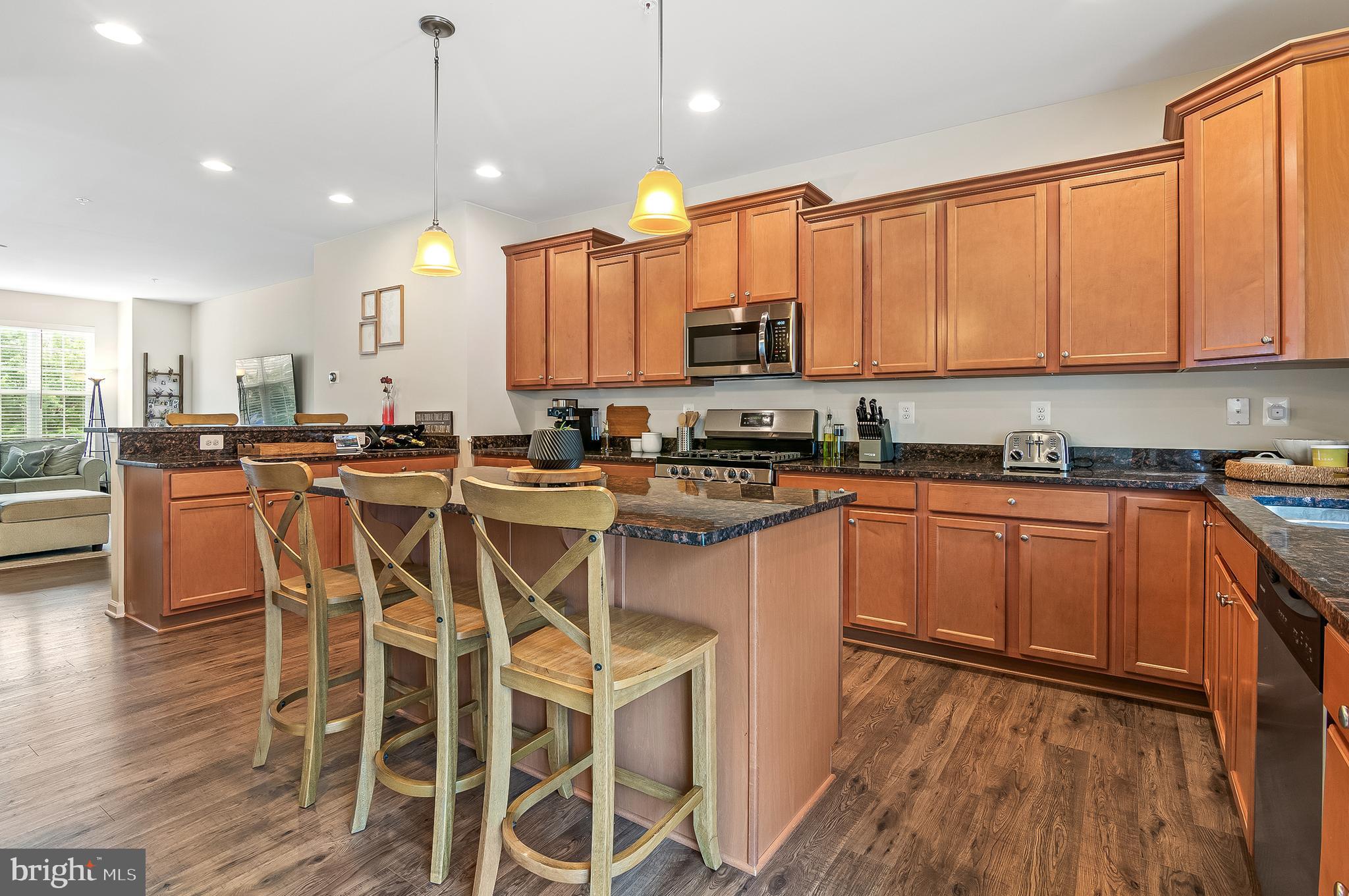 1022 Linden Drive Hanover, MD 21076 - Photo 18 of 42 a kitchen with stainless steel appliances kitchen island granite countertop a stove top oven a sink a dining table and chairs with wooden floor