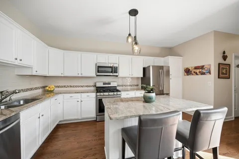 a kitchen with stainless steel appliances granite countertop a kitchen island a stove a table and chairs in it