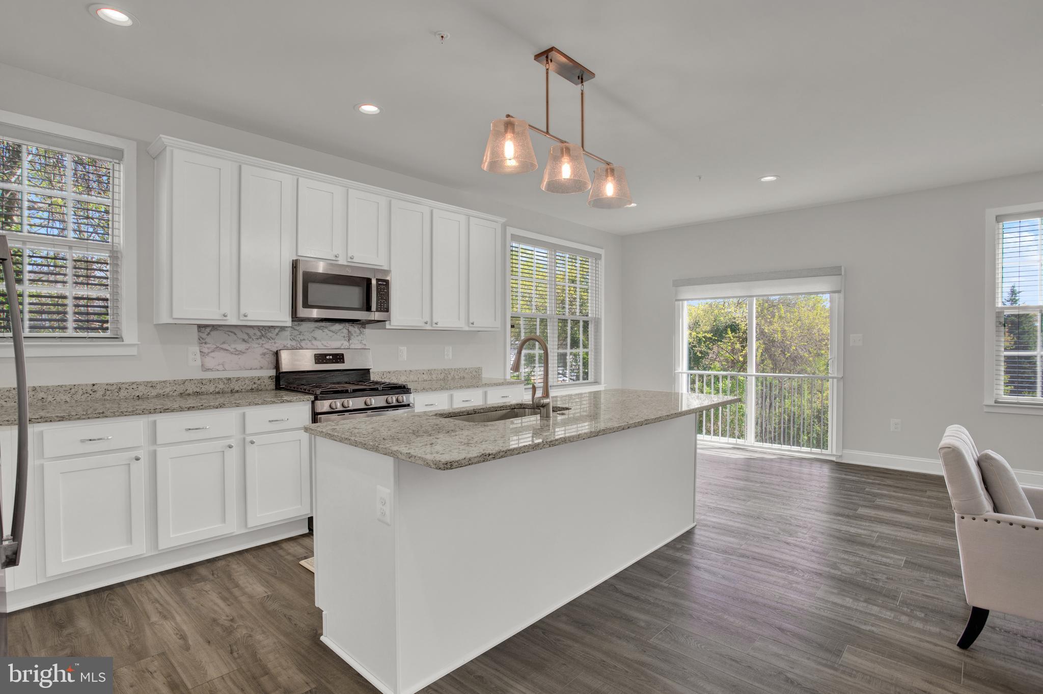 a kitchen with stainless steel appliances granite countertop a stove a sink a center island and a window