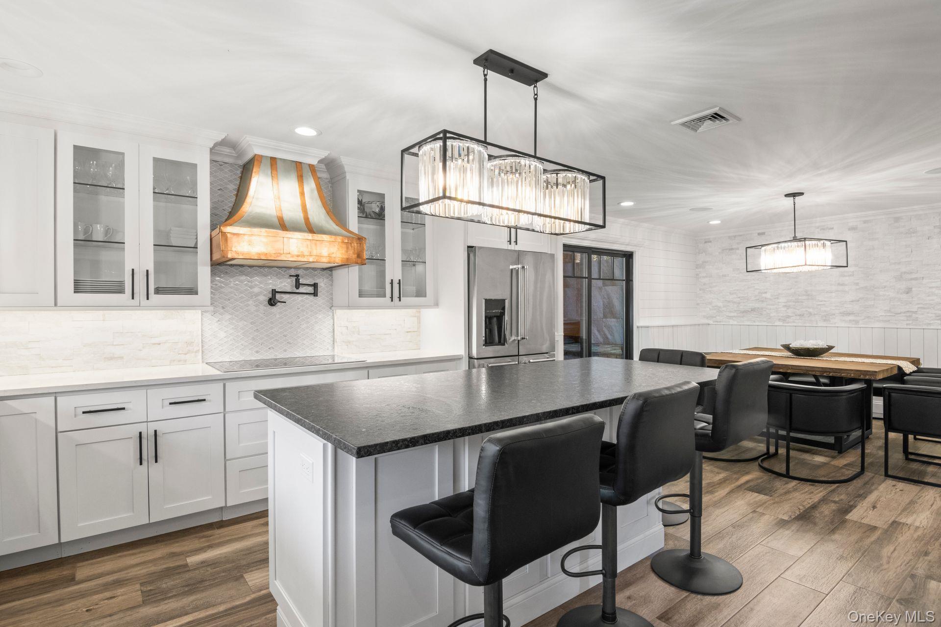 131 Fleets Cove Road Huntington, NY 11743 - Photo 5 of 41 a kitchen with kitchen island a stove a sink a dining table and chairs with wooden floor
