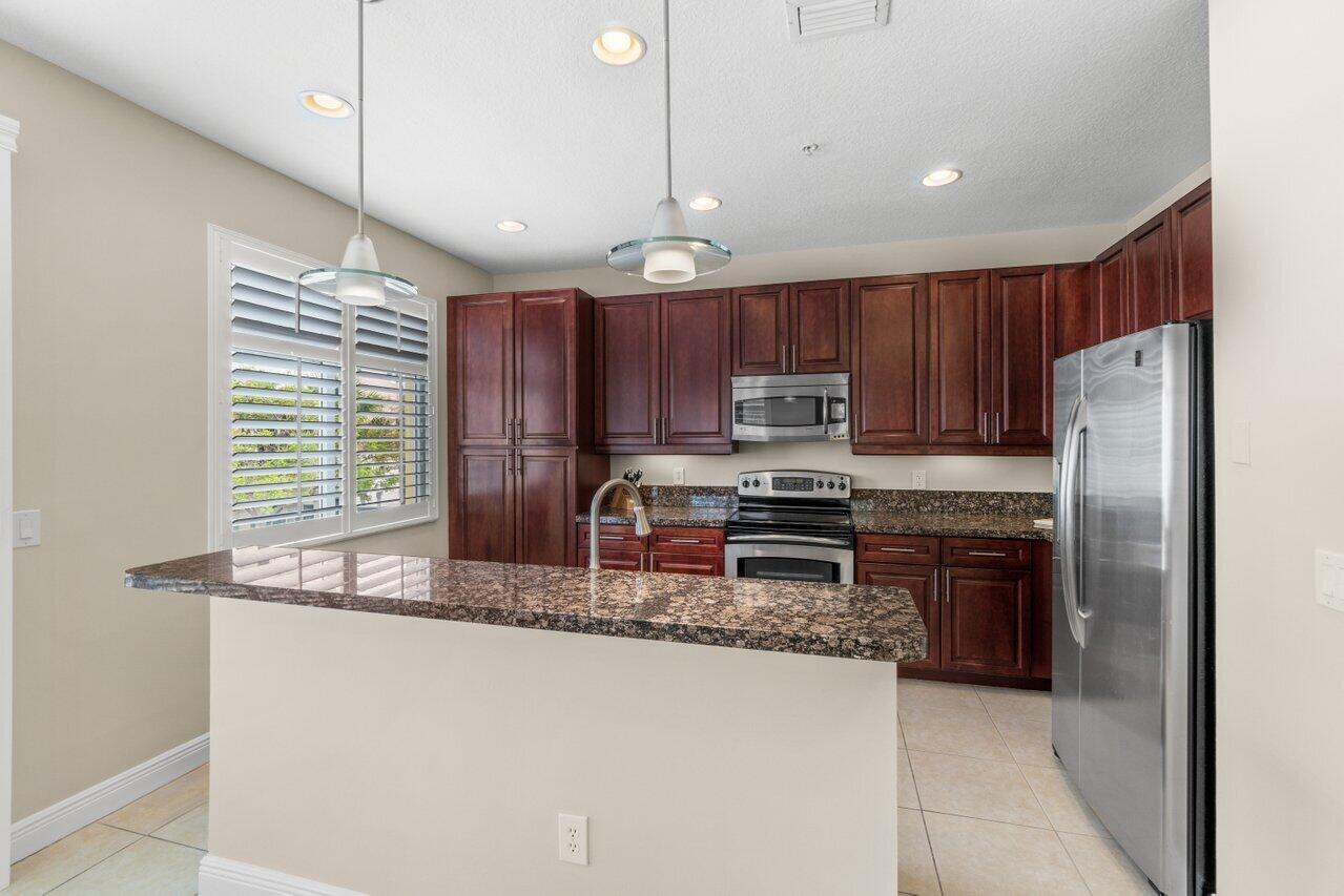 547 Northwest 35th Place Boca Raton, FL 33431 - Photo 11 of 37 a kitchen with kitchen island granite countertop stainless steel appliances a sink a stove a refrigerator cabinets and a counter top space