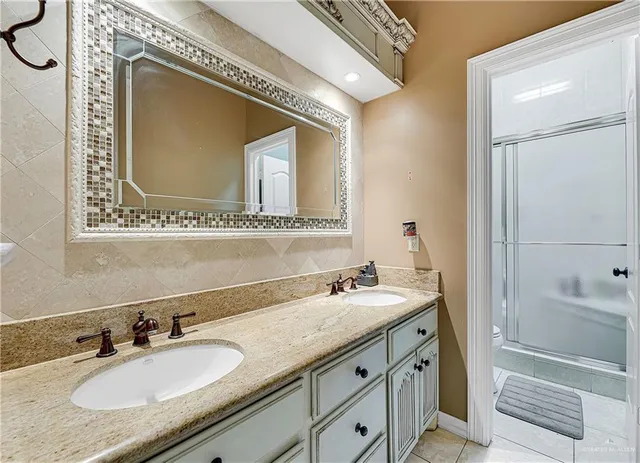a bathroom with a granite countertop double vanity sink and mirror