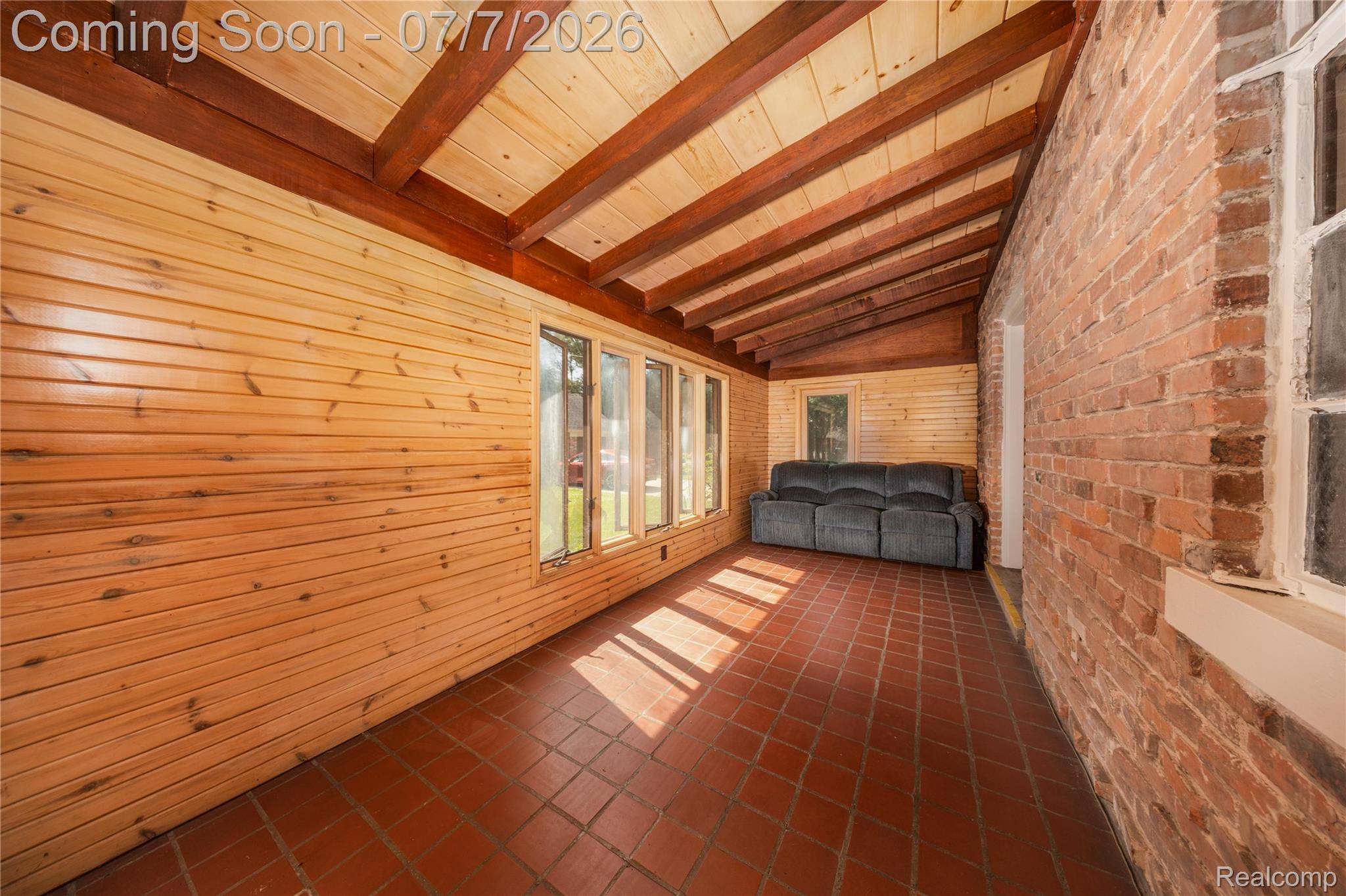16580 Westmoreland Road Detroit, MI 48219 - Photo 14 of 37 Enclosed porch featuring exposed brick wall, wood-paneled walls, wood-finish beamed ceiling, and terra cotta tile flooring