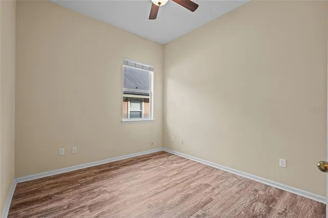 an empty room with a hardwood and ceiling fan