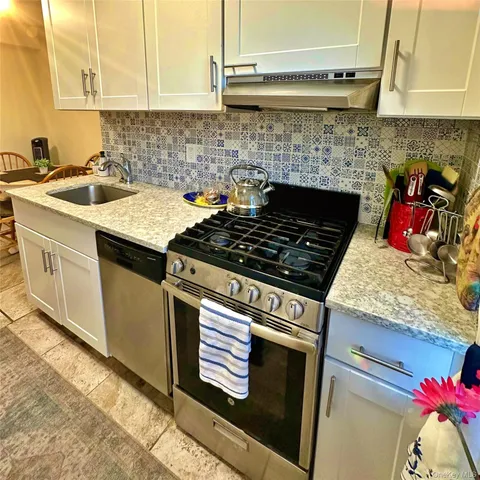 a kitchen with granite countertop stainless steel appliances a sink stove and cabinets