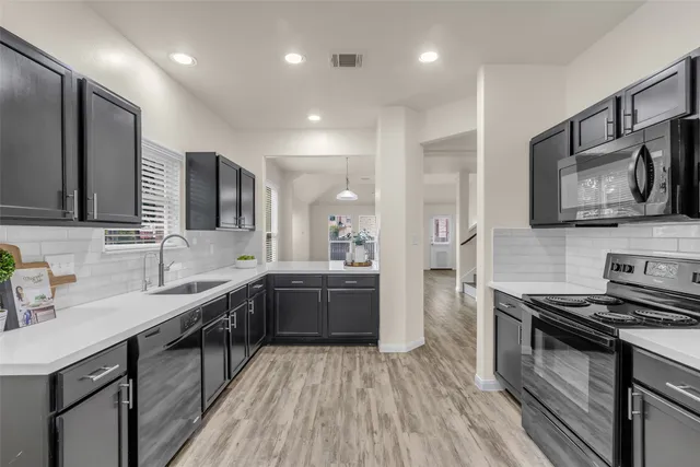 a large kitchen with stainless steel appliances granite countertop a sink stove and refrigerator