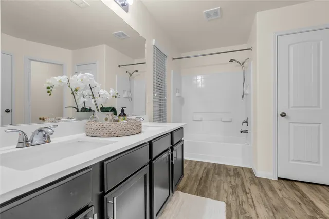 a bathroom with a sink double vanity granite tub shower and a mirror
