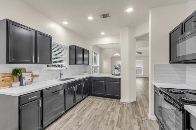 a large kitchen with stainless steel appliances granite countertop a lot of counter space and wooden floor
